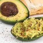 Avocado tagliato a metà su un piatto, ideale per abbassare il colesterolo alto.
