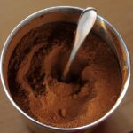 Tazza di caffè d'orzo in polvere con chicchi di orzo sul tavolo.