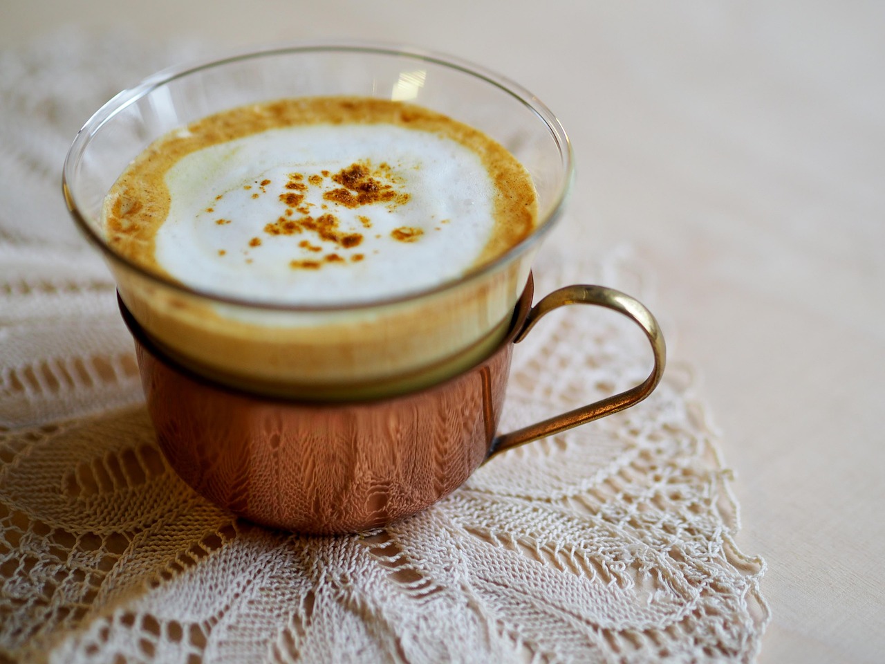 Bevanda di latte d'oro in una tazza, con spezie e curcuma in evidenza, su un tavolo di legno.