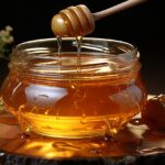 Un bicchiere d'acqua con miele su un tavolo, simbolo di salute e benessere serale.