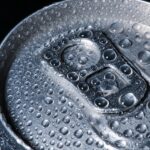 Un giovane sorseggia una bevanda energetica, con espressione preoccupata per i rischi per la salute.