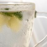 Tazza di acqua calda con limone su un tavolo, simbolo di una routine mattutina salutare.
